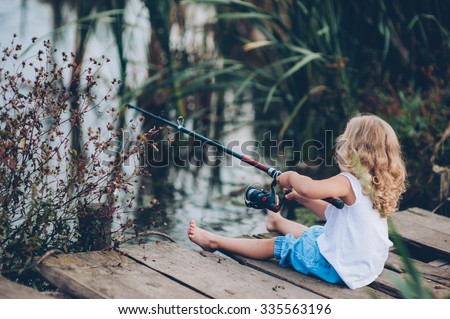 lonely little child fishing from wooden dock on lake