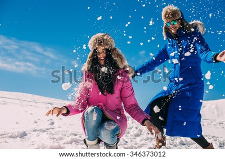 winter, two cheerful young girls having fun in the snow in the mountains