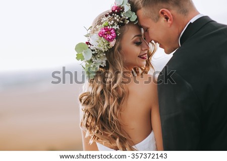 portrait of a girl and couples looking for a wedding dress, a pink dress flying with a wreath of flowers on her head on a background chicago garden and the blue sky, and they hug and pose