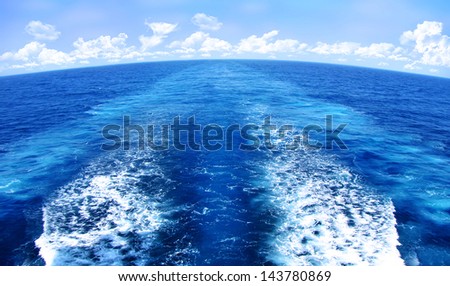 water movement wake pattern behind vessel boat and clouds in the horizon