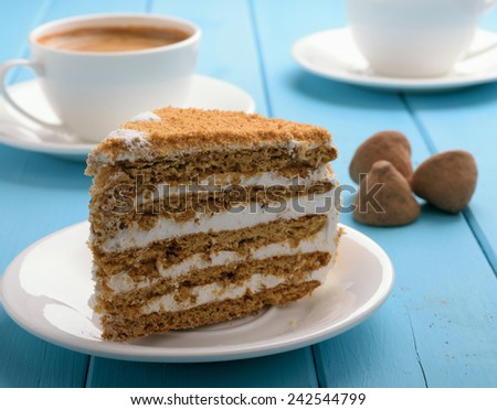 piece of cake on blue wooden table in the background cup of coffee and chocolate truffles