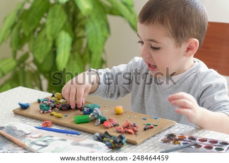 Little boy playing with clay, sculpting figures.