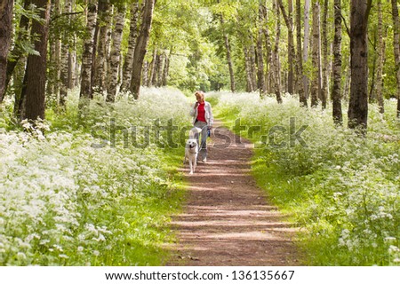 The woman walks with a dog in park