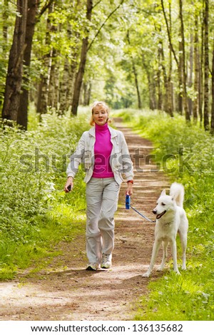 The woman walks with a dog in a wood