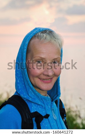 Portrait of the travelling woman of average years on a background of the evening sky