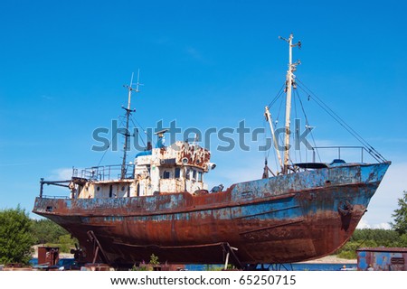 Old, rusty fishing launch on building berths in port