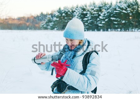 The woman pours from a thermos tea, in winter on walk