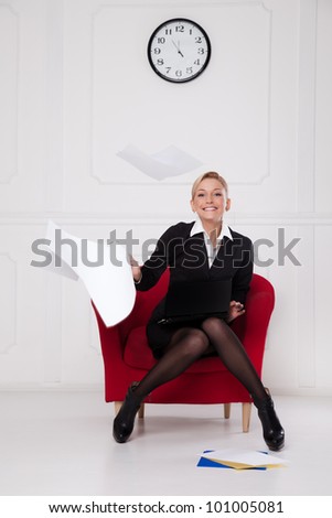 Business woman sitting in a chair and throws the paper into the air