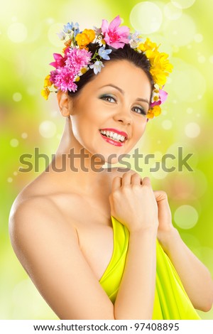 Portrait of beautiful smiling girl with flowers in hair on green bokeh background