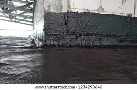 Waterproof coatings applied on flat roof concrete surfaces. There are several layers and layers of fiber mesh added to strengthen the bonding of the waterproofing layer.