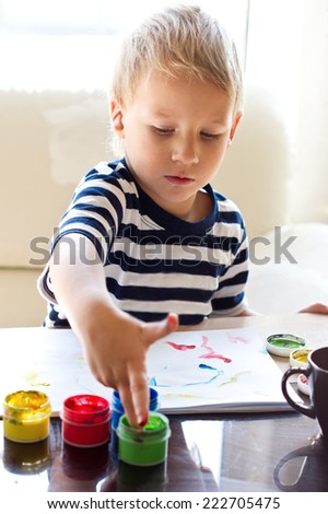 The boy is painting with fingers paints