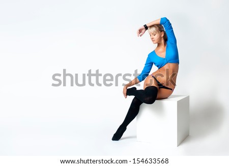 Sporty woman siting on the cube on white background