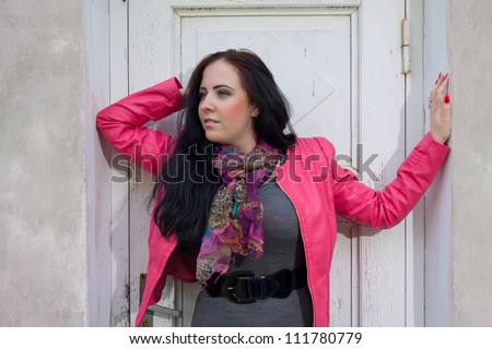 A beautiful girl looking to the side and standing in front of the closed white door.