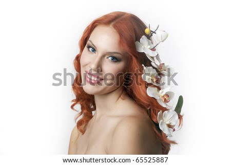 Young beautiful red haired woman smiling with an orchid in her hair, isolated on white background