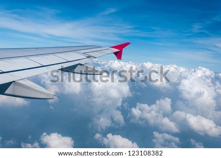 Wing of the plane on sky background - plane wing with cloud patterns - view from the window of a plane of the wing, the sky - View of jet plane wing
