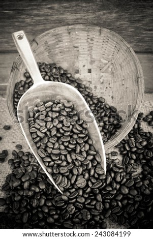 Coffee beans and silver scoop on old wood background with retro black and white filter effect