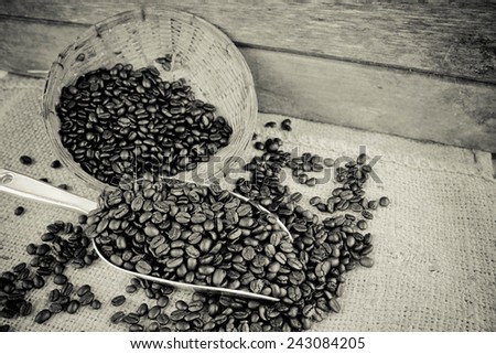 Coffee beans and silver scoop on old wood background with retro black and white filter effect