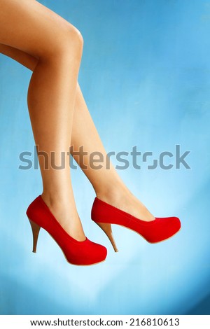 Perfect female legs wearing high heels isolated on blue  background