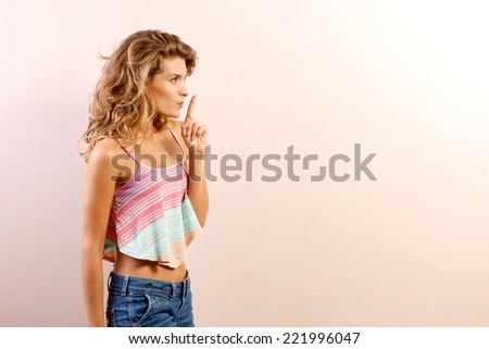 Closeup of serious woman placing finger on lips, pointing at you as if to say, shhhhh, quiet, silence . Human face expression, sign, emotion, feelings, body language with copyspace