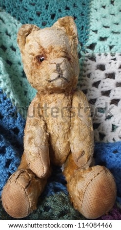 Old teddy bear sat  on blue crochet blanket
