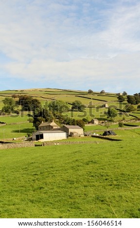 Rural view near Nidderdale, North Yorkshire, England, Farm house and land in rolling green hills beneath an early autumn blue sky.