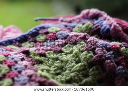 Crochet blanket in pinks, purple and greens, shallow depth of field , abstracted image