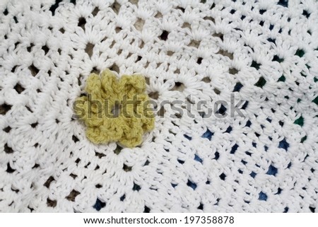Yellow green crocheted flower on a white crochet afghan , using different stitches