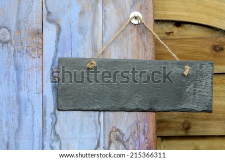 rectangle blank slate sign hanging on a garden shed door, painted in weathered  blue paint,