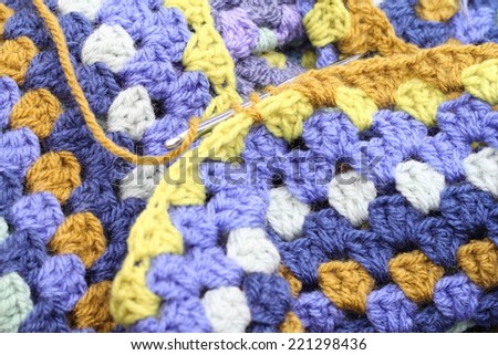 Crocheting, crochet hook making an afghan blanket in shades of blues and browns, a vintage craft