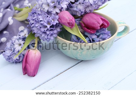 Blue, lilac hyacinth and dusky pink tulips in a green ceramic cup  bowl on wooden pale duck egg blue painted wooden boards , pretty spring image , shallow depth of field , mothers day