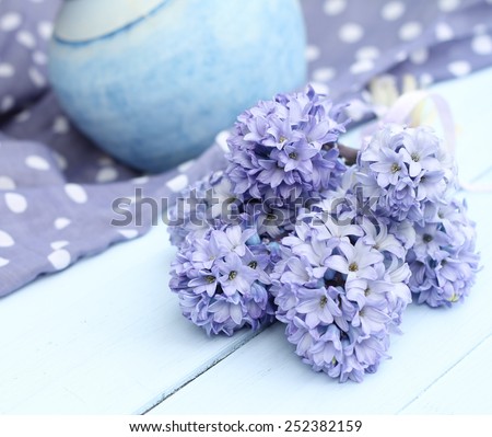 Blue lilac hyacinth on wooden pale duck egg blue painted wooden boards ,dusky blue ceramic vase and spotty periwinkle fabric in background, pretty spring image , shallow depth of field , mothers day