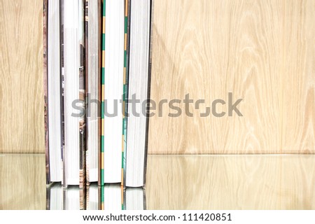 Book stack against with reflection on glass base and wood background