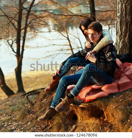 Portrait of young romantic couple sitting in forest enjoying themselves - Outdoor