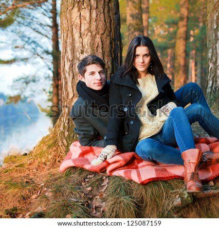 Spring outdoor portrait of young pair. Boy and girl in the spring forest sitting on vintage cover