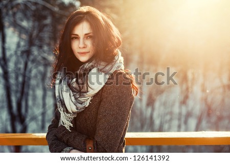 Sunny outdoor winter portrait of young attractive woman. Pretty girl smiling in winter on the street.