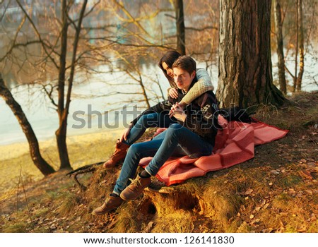 Young couple in love posing in winter. Sensual boy and girl sitting on the ground in spring park