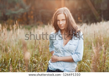 Outdoor summer portrait of young pretty woman standing in grass on the field
