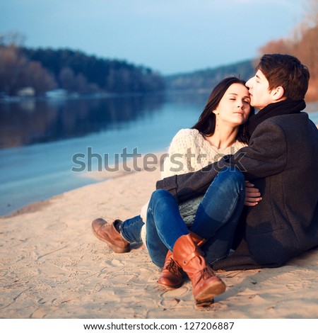 Young attractive couple in love posing in cold spring on the beach