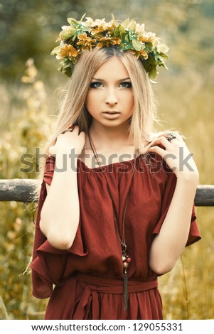 Young pretty blond outdoor spring portrait. Girl with flowers on her head
