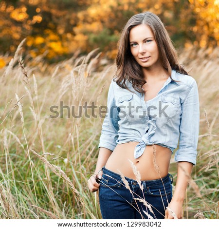 Young pretty brunette woman posing outdoor in summer meadow. Sensual girl posing in park