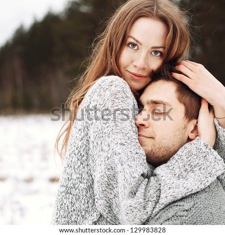 Outdoor happy couple in love posing in cold winter weather. Young boy and girl having fun outdoor