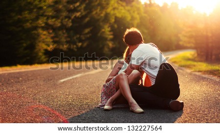 Young couple in love kissing on the road in summer evening