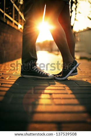 Young Couple In Love Standing On The Street In Gumshoes In Summer Sunny Warm Weather.