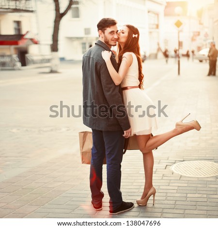 Young outdoor fashion portrait of beautiful couple kissing on the street