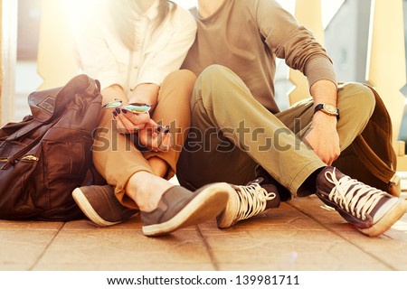 Young couple sitting on the ground in summer. Vintage sunny colors.