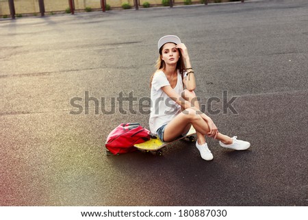 Young pretty happy smiling hipster girl posing outdoor with skateboard in summer