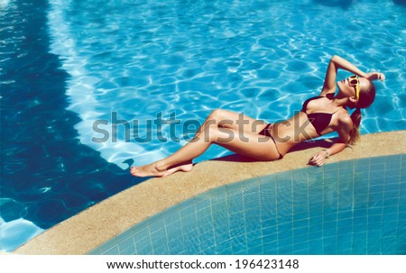 Fashion outdoor portrait of pretty sexy brunette tanned woman having fun in summer on tropic island close to swimming pool with clear deep blue water Full relax vintage and happiness