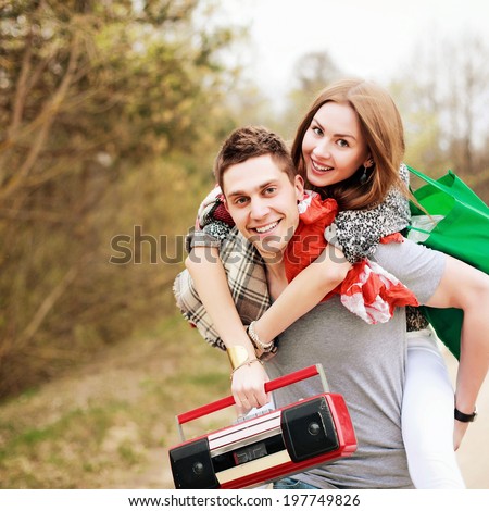 Young pretty couple in love having fun outdoor in summer forest together smiling dancing and listening music with red boom box recorder