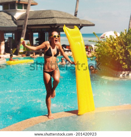Young pretty sexy woman in bikini have fun on the pool in summer laughing and dancing in water splash