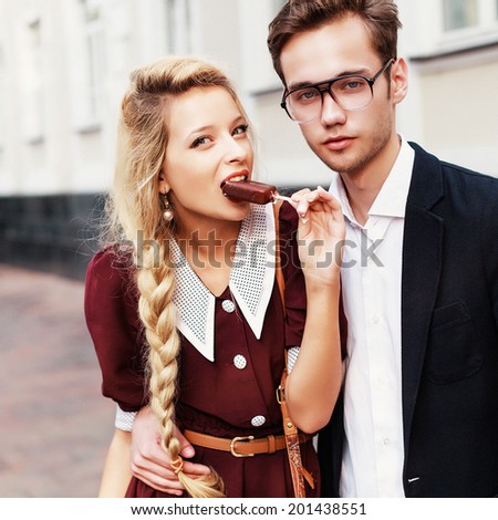 Couple in love pretty young blond woman having fun with her handsome hipster style boyfriend eating chocolate ice cream and have fun on the street in summer